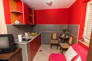 a kitchen with red walls and a table and a tv at Adzic Apartments in Budva