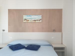 a bedroom with a bed with two blue pillows at Caletta sul Mare in La Caletta