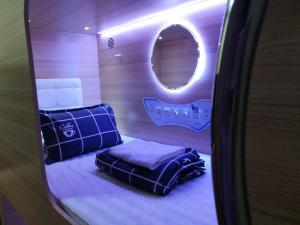 um pequeno quarto com uma cama e um espelho redondo em CapsulePod@Aljunied em Singapura