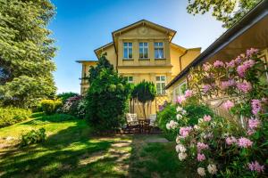 an exterior view of a yellow house with flowers at Willa Dusia in Międzyzdroje