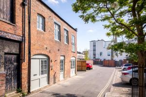 an alley with brick buildings and cars parked on a street at Oxford Passage Coach House in Cheltenham