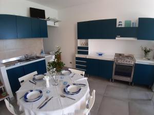 a kitchen with a white table and blue cabinets at Mavì in Cava D'aliga