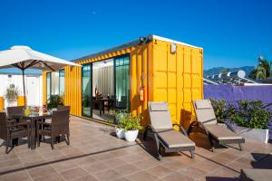 a yellow house with a table and chairs on a patio at Container Inn Hotel Aeropuerto in Puerto Vallarta