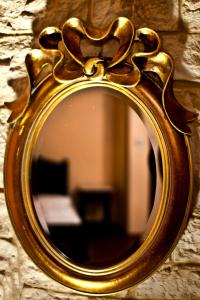 um espelho com uma moldura dourada numa parede de pedra em Stavraetos em Sirako
