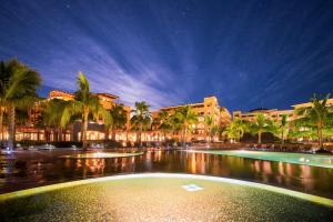 a large pool with palm trees and buildings at night at Villa del Palmar at the Islands of Loreto in Loreto