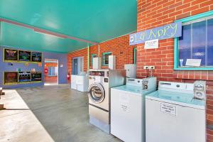 a laundry room with washing machines and a brick wall at Caravella Backpackers in Cairns