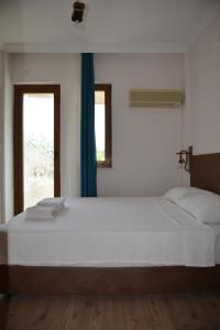 a bedroom with a large white bed and a window at Double Comfort Otel in Muğla