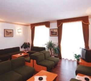 a living room with a couch and a tv at Albergo Scarpone in Forni Avoltri