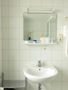a white bathroom with a sink and a mirror at Uns Gartenhus mit Blick auf das Meer in Thiessow