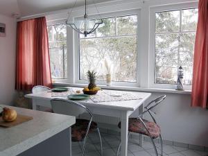 a kitchen with a white table and chairs and windows at Uns Gartenhus mit Blick auf das Meer in Thiessow +7 photos