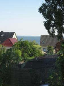 a group of houses and trees with the ocean in the background at Uns Gartenhus mit Blick auf das Meer in Thiessow
