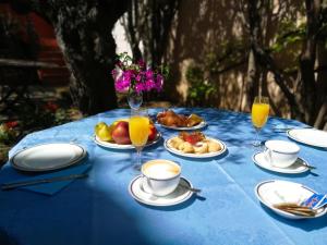 Hotel Il Vecchio Mulino في ارباتاكس: طاولة زرقاء مع أطباق من الطعام وكؤوس من عصير البرتقال