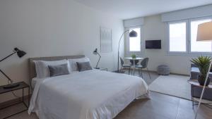 um quarto com uma cama branca, uma mesa e cadeiras em Erïk Langer Pedrocchi Suites em Pádua