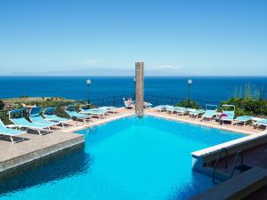 a large swimming pool with lounge chairs and the ocean at Hotel Sirius in Taormina