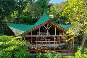 un bâtiment avec un toit vert dans une forêt dans l'établissement Aguila de Osa Rainforest Lodge, à Drake