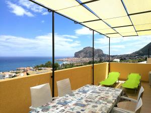 een tafel en stoelen op een balkon met uitzicht op de oceaan bij Casa Panoramica Santa Lucia in Cefalù