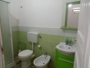 a green and white bathroom with a toilet and sink at La Melagrana in Castellammare del Golfo