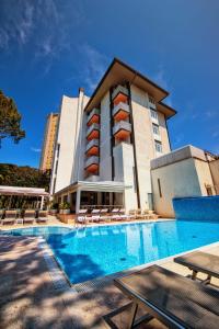 a hotel with a swimming pool in front of a building at Hotel Bella Venezia Mare in Lignano Sabbiadoro