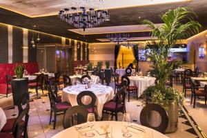 a restaurant with white tables and chairs and chandeliers at Best Western Plus Hotel Modena Resort in Formigine