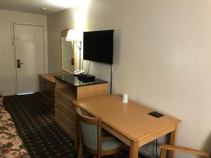 a hotel room with a desk and a table with a television at Blue Falls Motel in Tonawanda