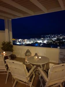 a table and chairs with a view of a city at night at Katerina Apartments & Studios in Naousa