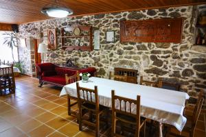 Casa Raúl Lires في Lires: غرفة طعام مع طاولة وجدار حجري