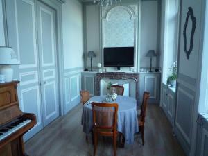 a dining room with a table and a piano at Château de Plessier-Roza in Le Plessier-Rozainvillers