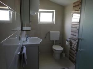 a bathroom with a sink and a toilet and a window at Apartment Kurelic in Rab
