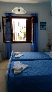 1 dormitorio con cama con sábanas azules y ventana en Christina Pansion, en Kokkari