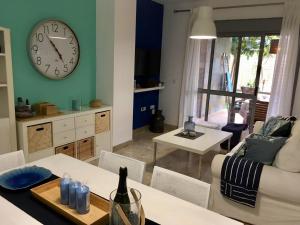 ein Wohnzimmer mit einem Tisch und einer Uhr an der Wand in der Unterkunft oasis del toyo golf&beach private garden wifi in Retamar