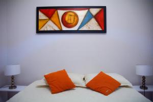 un cuadro sobre una cama con dos almohadas naranjas en Petit Apart Villa Regina en Villa Regina