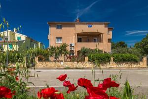 a building with red flowers in front of a street at Vila Milla in Premantura