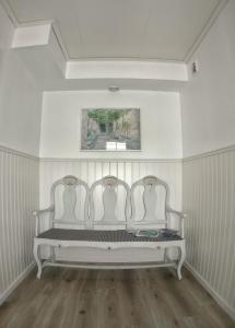 two white benches in a room with a painting at Lundsbrunn B&B in Lundsbrunn