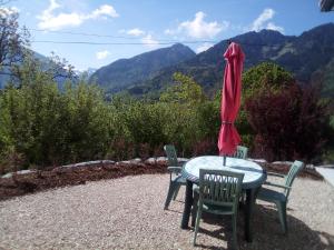 un tavolo con due sedie e un ombrellone rosso di le relais du tilleul a Chevenoz