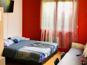a bedroom with a bed with red walls and a window at Beaux studios sur les quais in Alfortville