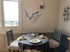 mesa de comedor con un pájaro en la pared en La Poupardoise, en Honfleur