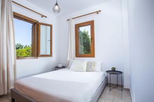 a white bedroom with a bed and two windows at Apartment Ivy Kallithea in Rhodes Town