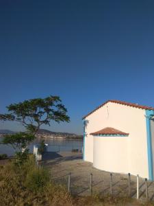 a white building with a tree next to a body of water at DREAM & HARMONY in Artemida