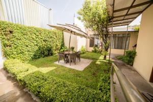 un jardín con mesa, sillas y sombrilla en Hotel Elizabeth Central, en Aguascalientes