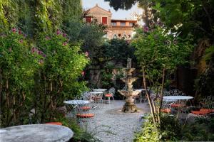 un jardín con mesas, sillas y una fuente. en Hotel Flora, en Venecia