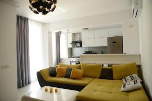 a living room with a yellow couch and a kitchen at Milan in Mamaia Nord