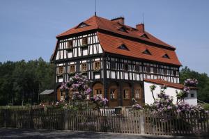 a building with a red roof with flowers in front of it at Zagroda Kołodzieja in Zgorzelec