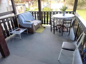 uma varanda com um sofá, cadeiras e uma mesa em Recanto dos Fernandes em Monte Verde