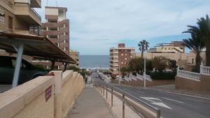 una via cittadina con edifici e l'oceano sullo sfondo di Apartamento en Arenals Del Sol ad Arenales del Sol