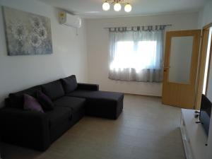Una sala de estar con un sofá negro y una ventana. en House Mia, en Starigrad-Paklenica