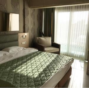 a bedroom with a bed and a chair and a window at Marin-A Hotel & Spa Turgutreis in Turgutreis