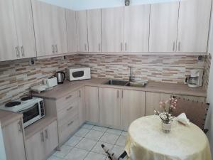 cocina con armarios blancos, mesa y fregadero en An amazing place for you! GIANNAS HOME, en Évyiros