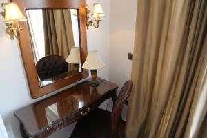 1 dormitorio con escritorio, espejo y lámpara en Gondola Hotel & Suites, en Amán