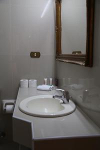 
a white sink sitting under a mirror in a bathroom at Gondola Hotel & Suites in Amman
