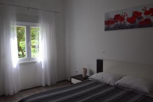 a white bedroom with a bed and a window at Apartman Ana in Sali
